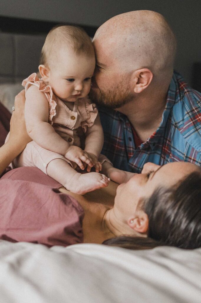Dad kissing baby during family photoshoot at home