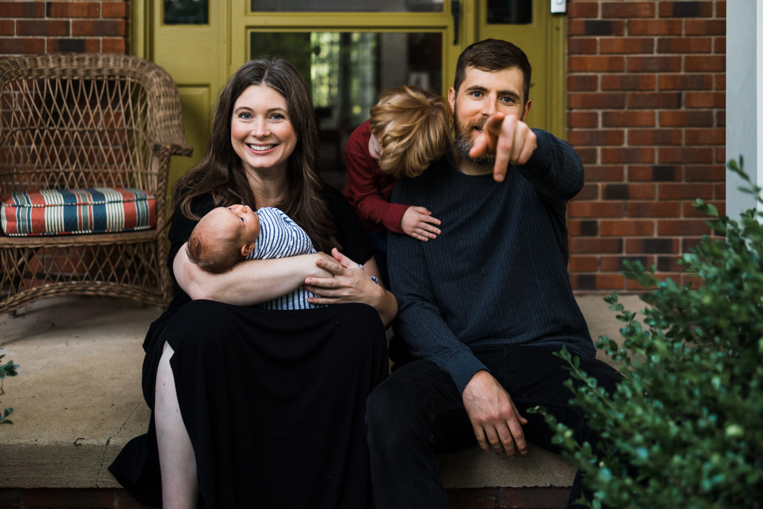 Family of four with new baby on front porch during an in-home newborn session
