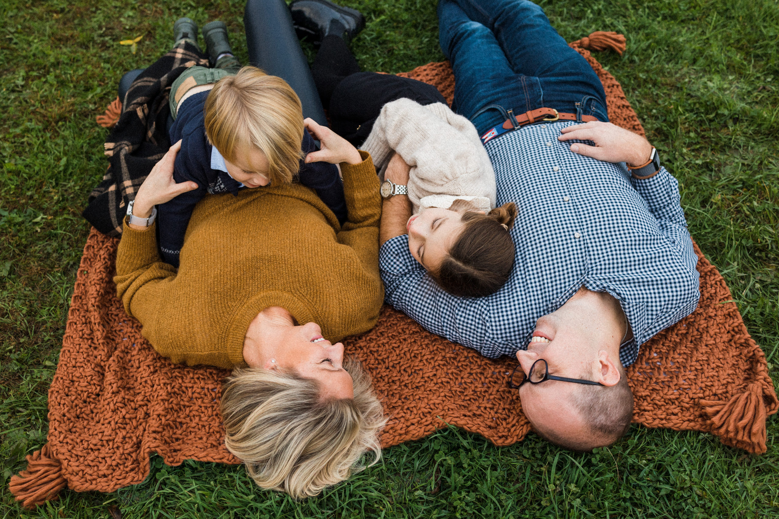 Family of four laying on blanket in field