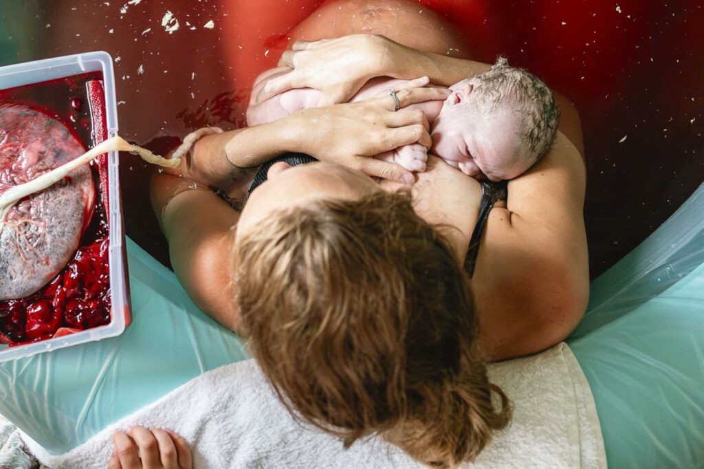 Mother nursing baby in birthing pool after home birth
