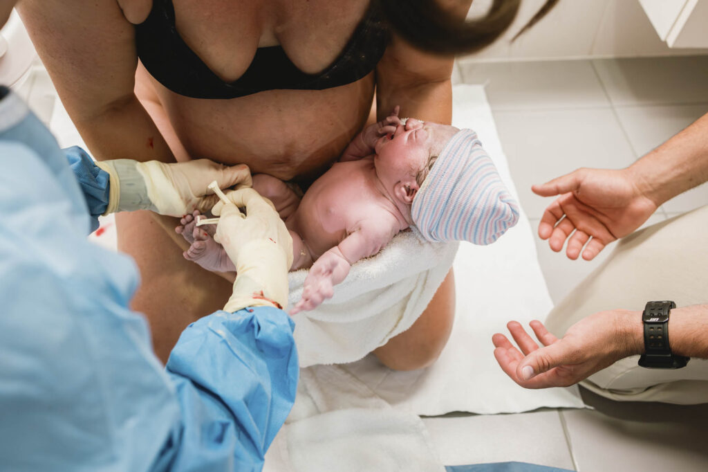 Mom holding newborn baby in hospital bathroom
