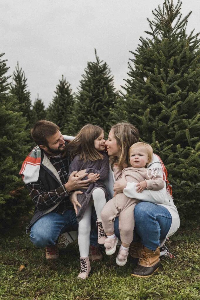 Family cuddled up in front of Christmas tree