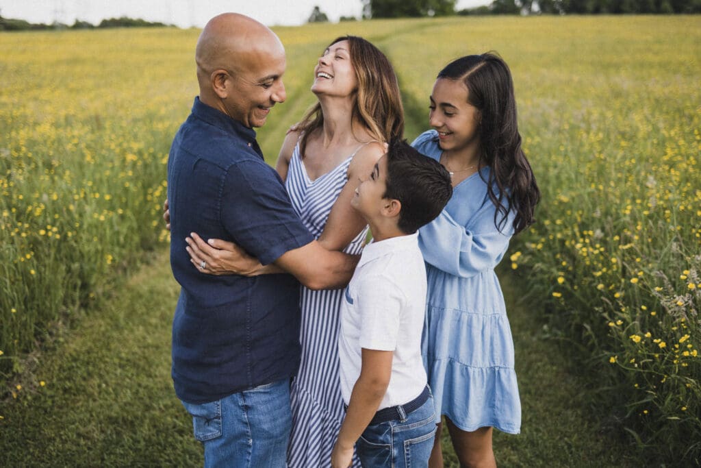 Family laughing in yellow flower field during spring family photos