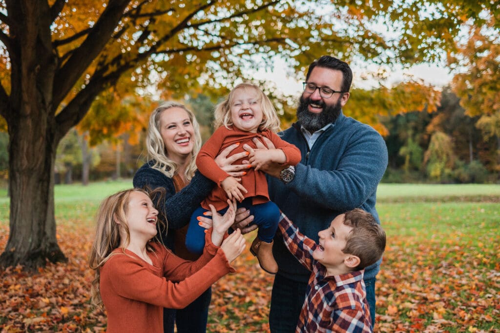 Family pplaying during family photo session in meadow 
