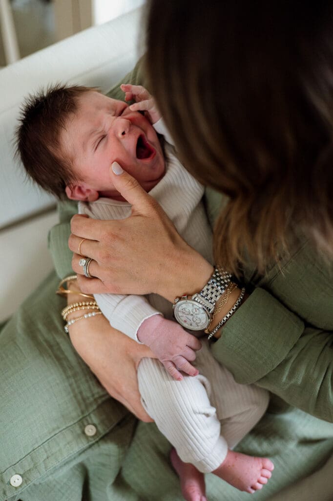 Mom stroking newborn baby's cheek while rocking in rocking chair
