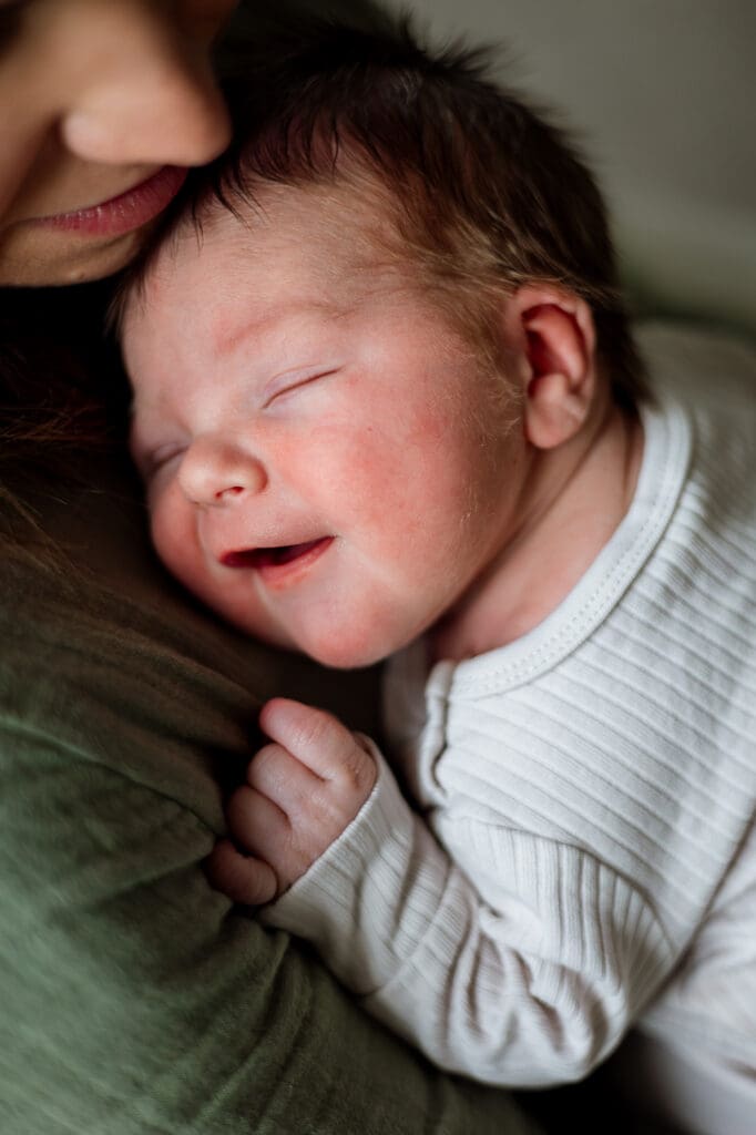 Portrait of newborn baby smiling in mom's arms during Chagrin Falls photography session
