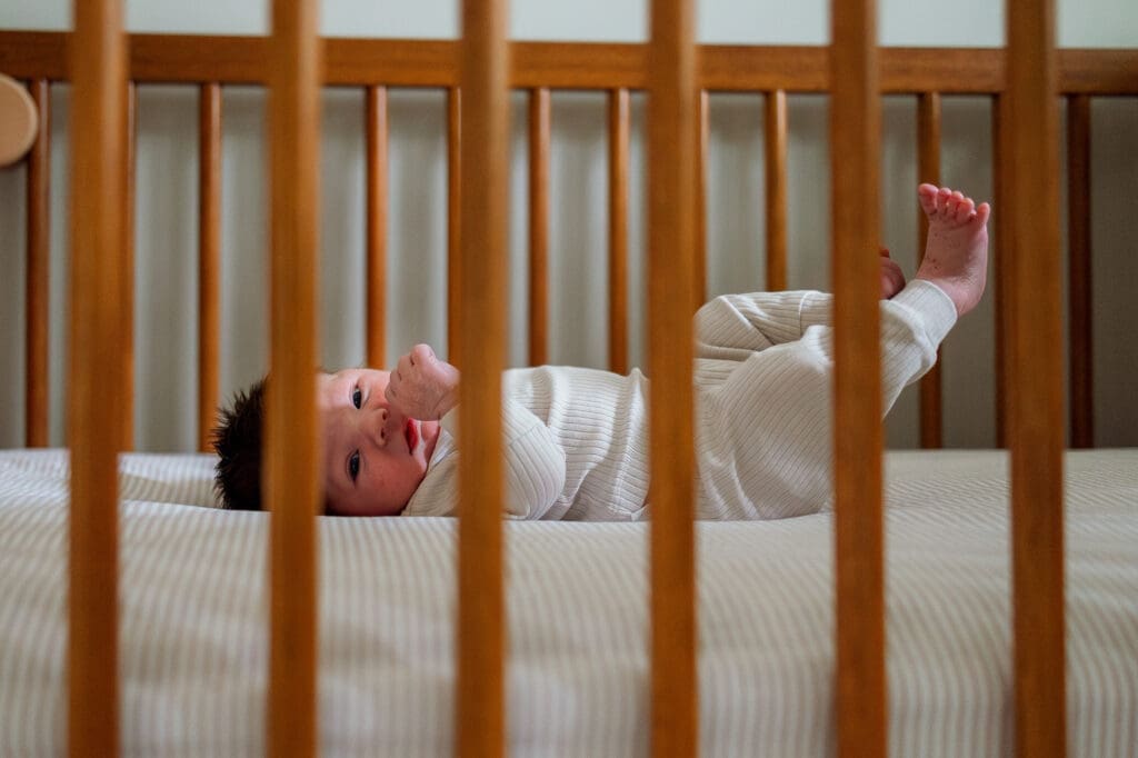 Newborn baby laying in crib looking at camera during Chagrin Falls newborn photography session
