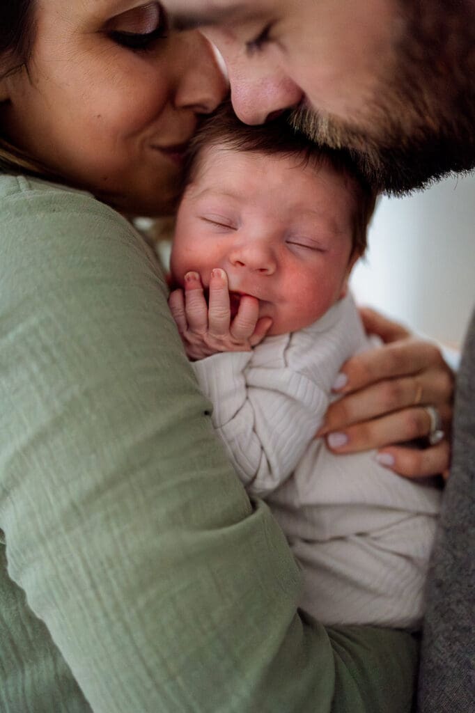 Close up portrait of of parents kissing newborn during Chagrin Falls newborn photography session
