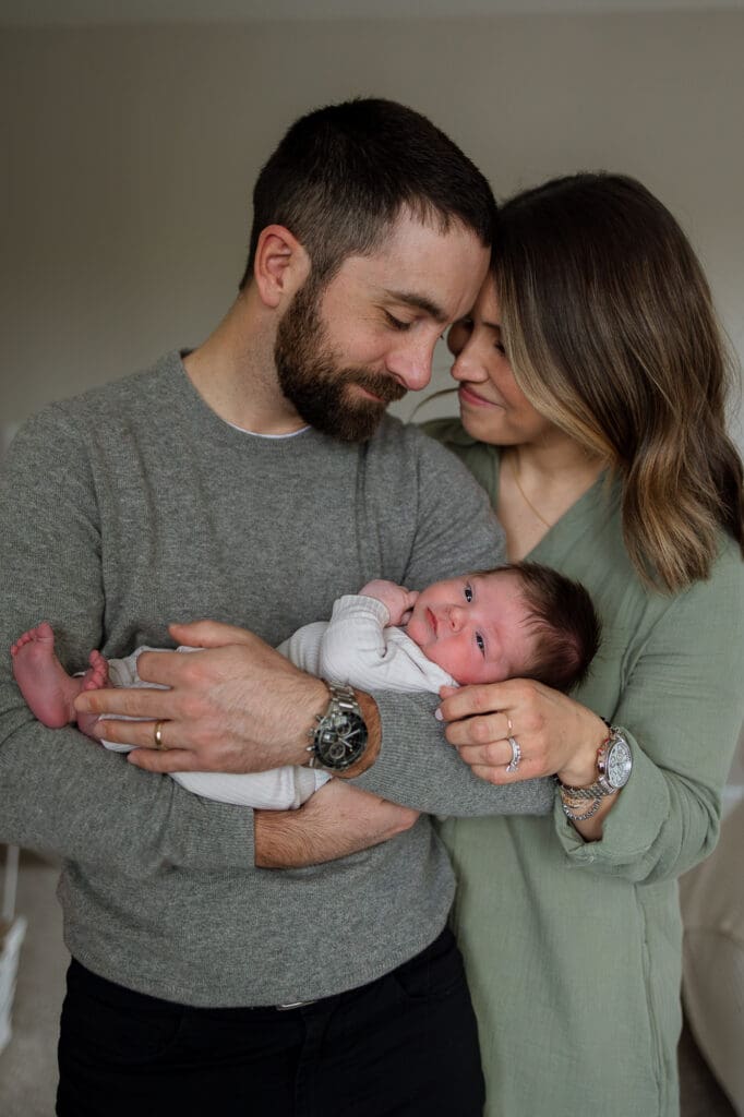 Mom and dad snuggling with newborn baby during Chagrin Falls newborn photography session
