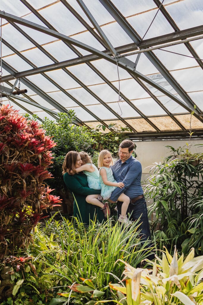 Family of four hugging at Rockefeller Park Greenhouse in Cleveland, OH.