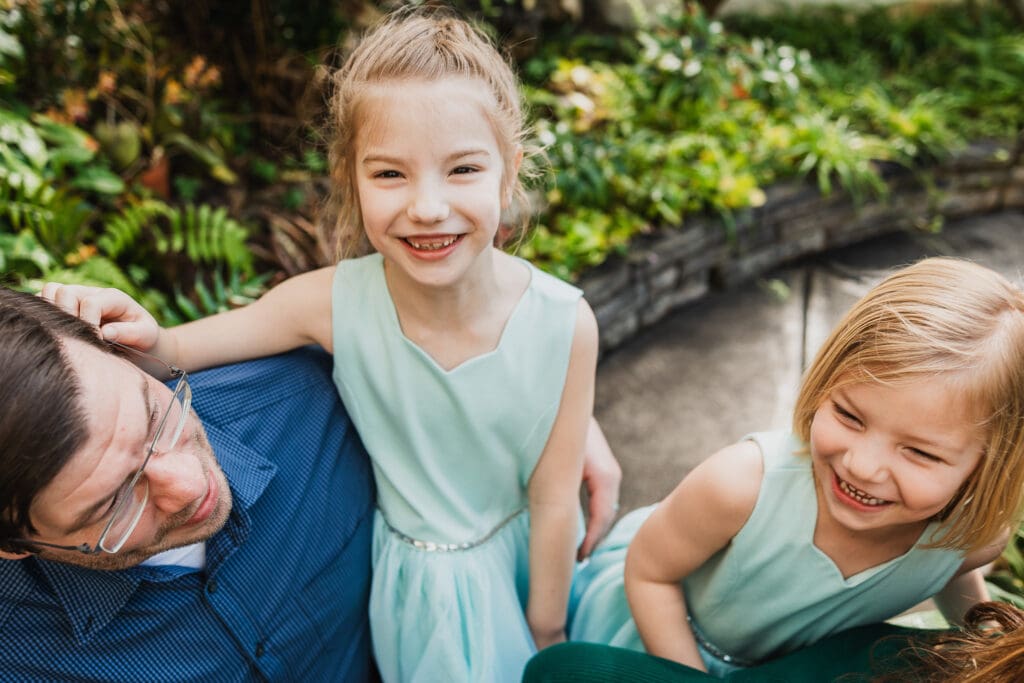 Sister laughing with parents in greenhouse
