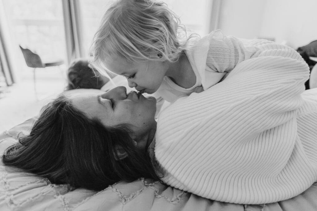 Daughter kissing mom on bed