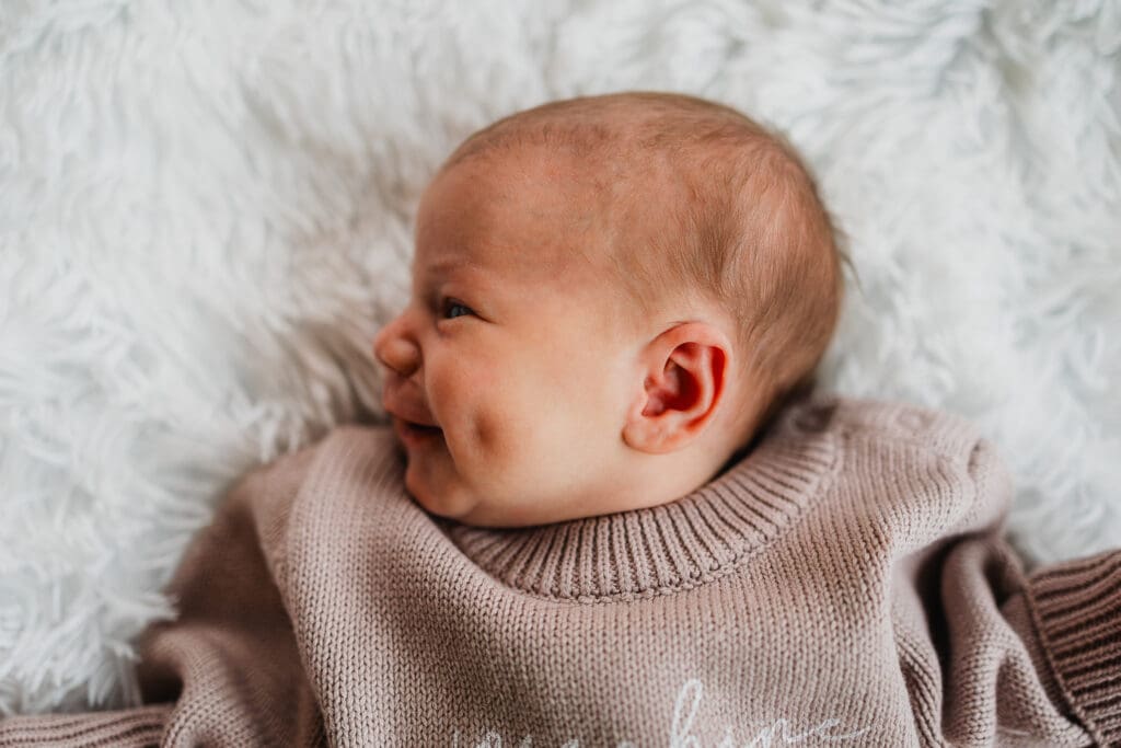 Baby smiling on floor during in-home newborn photography session