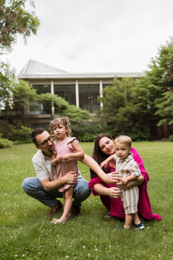 Family of four squatting in the grass at Cleveland Botanical Garden family photoshoot. 