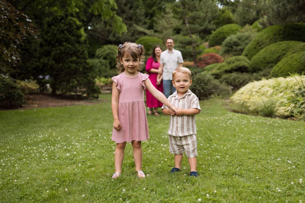 Kids standing holding hands with mom and dad in background during session at Cleveland Botanical Garden