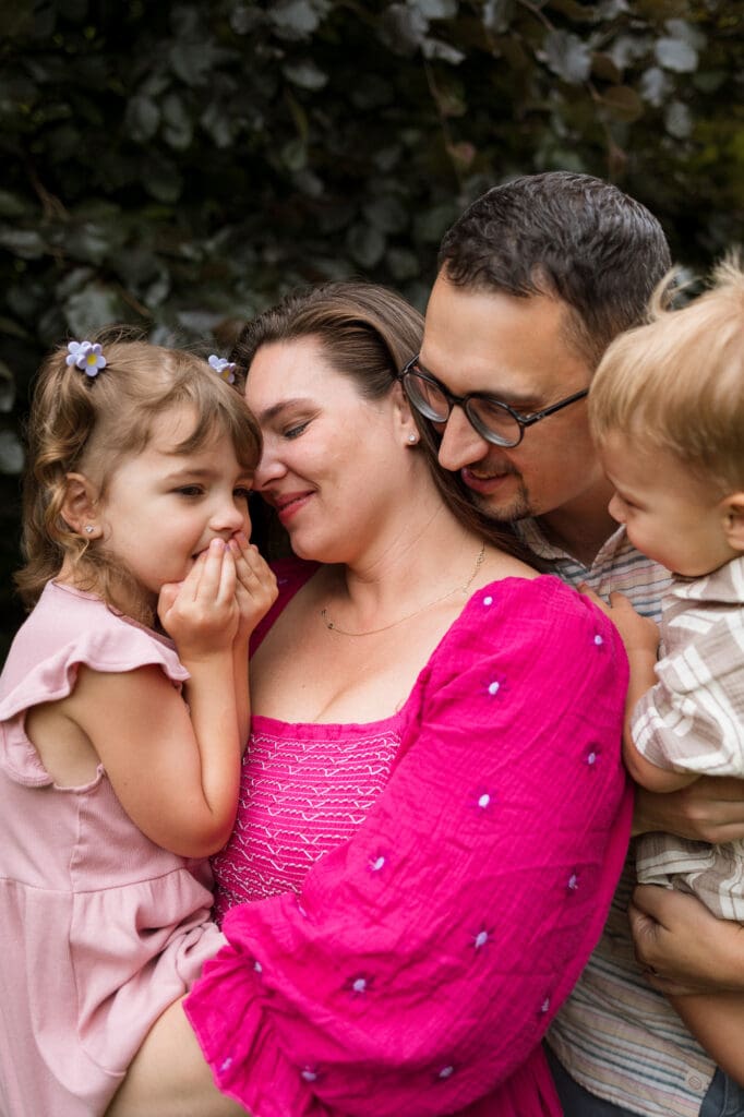 Family of four snugging in front of tree