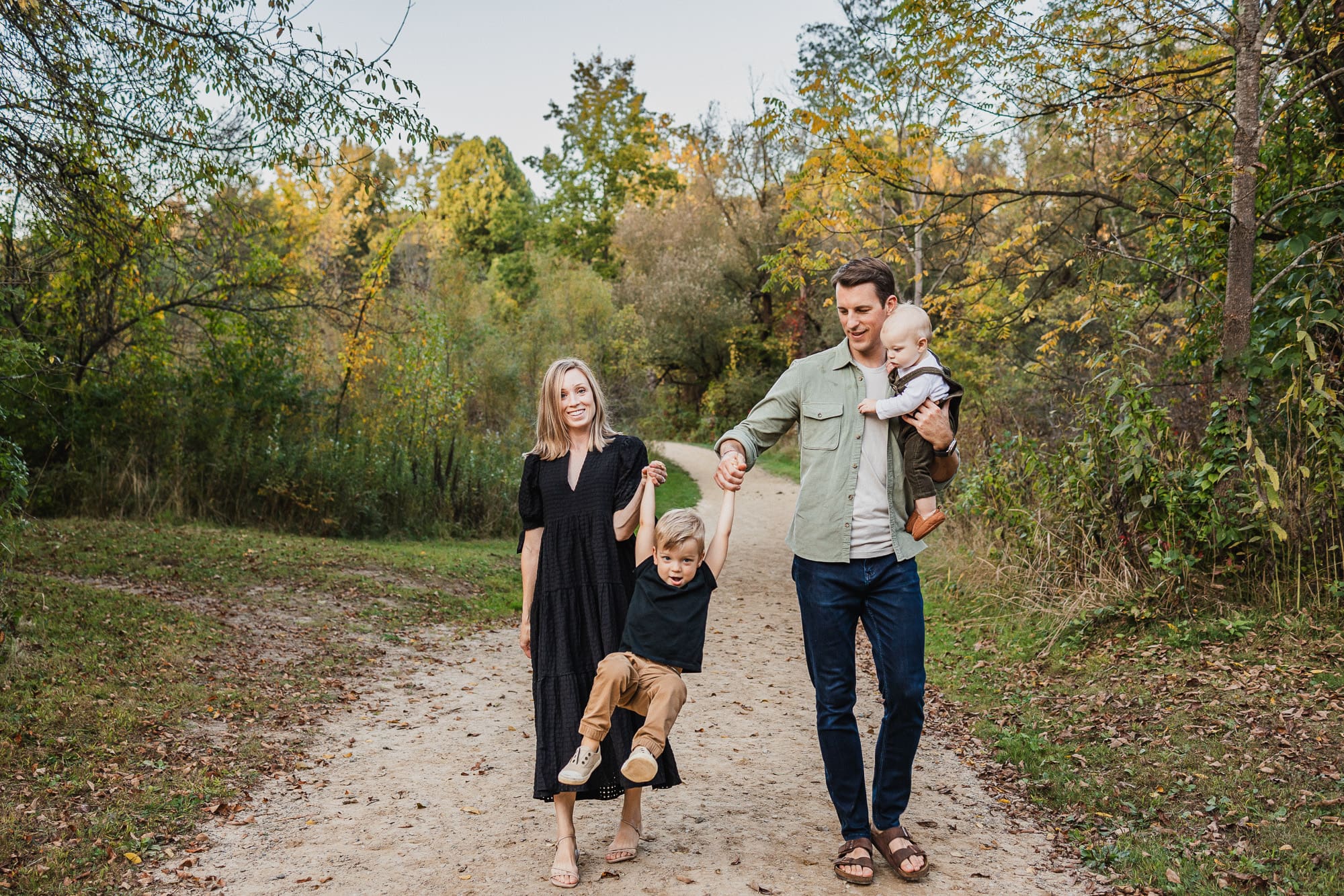 Mom and dad swinging toddler during fall family photos at Jackson Field in Cleveland