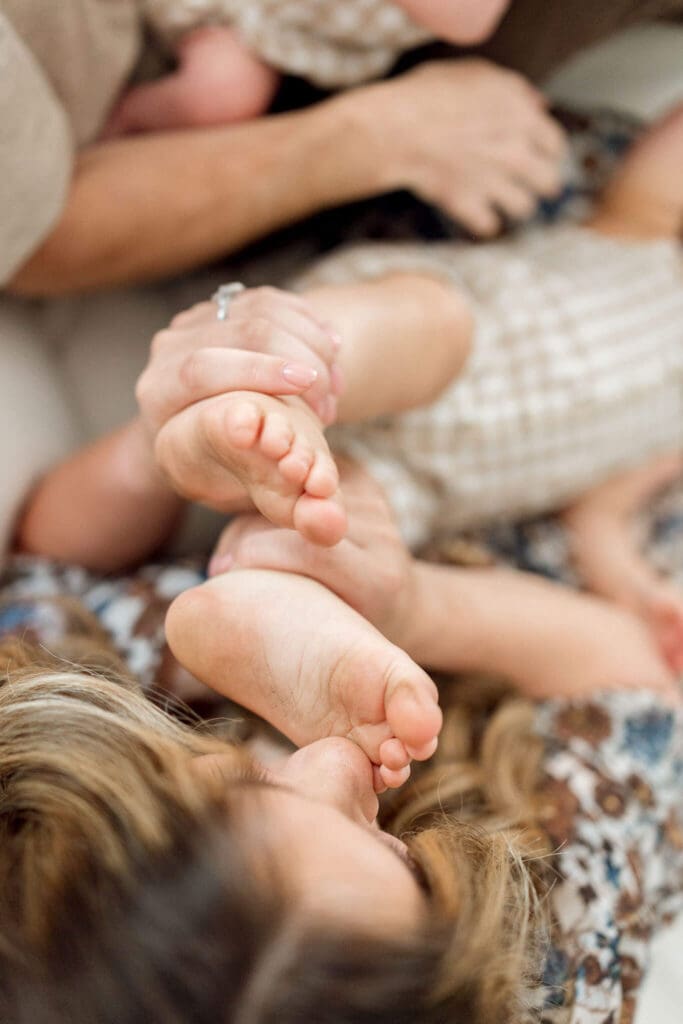 Mom kissing toddler's toes during in-home family photos in Cleveland. 