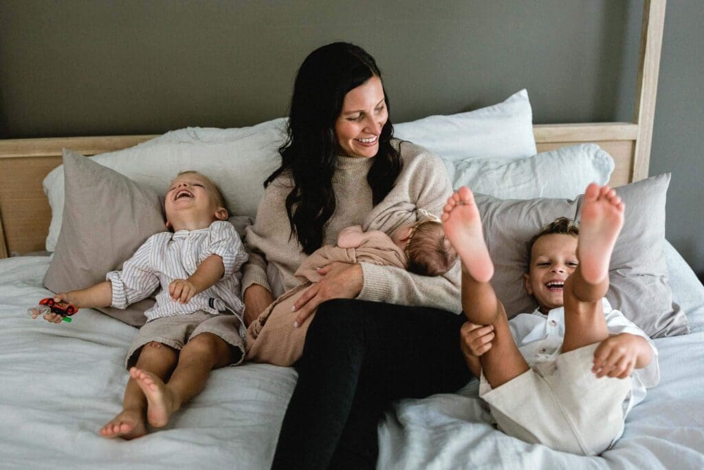 Mom holding newborn while big brother act silly during in-home family photo session in Cleveland. 