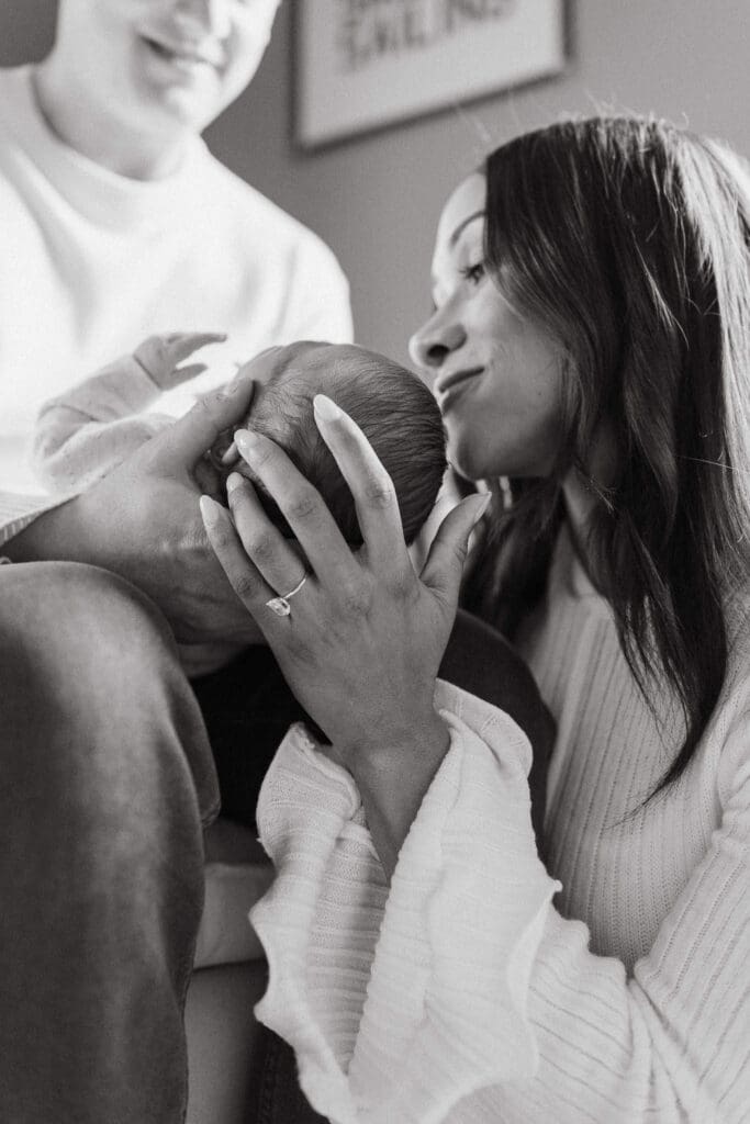 A close-up moment of a mother’s hands cradling her newborn’s head—highlighting the intimacy and tenderness of the newborn stage.
