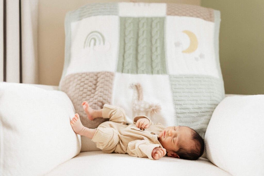 A newborn peacefully sleeping in a cozy nursery chair—a quiet reminder of the stillness and softness of the newborn stage.