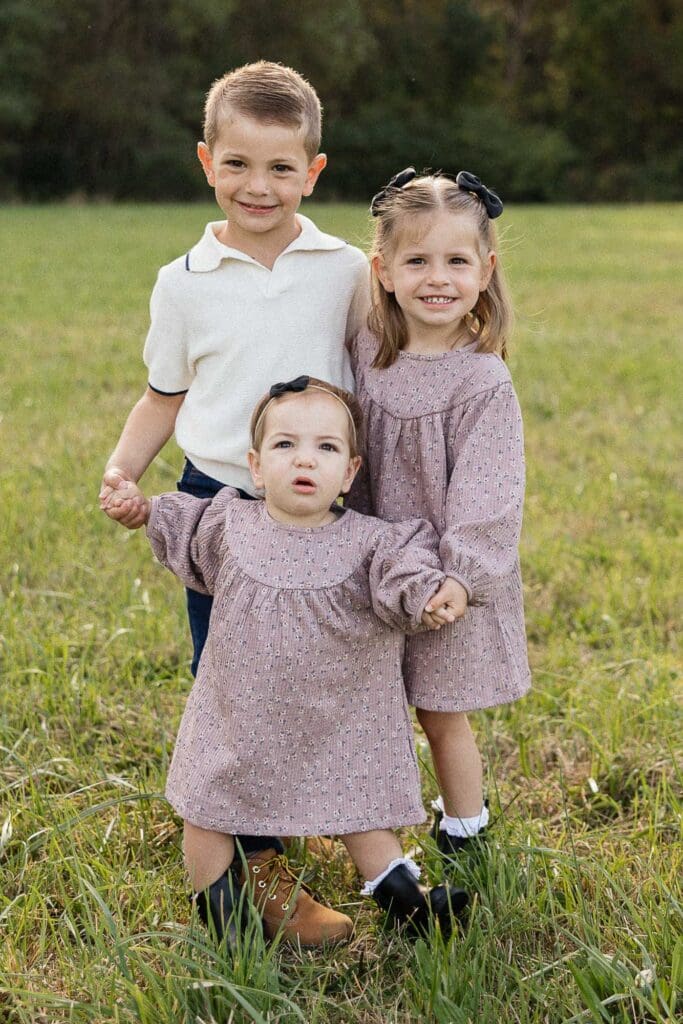 Siblings snuggling together in a fall field during a Cleveland family photoshoot.