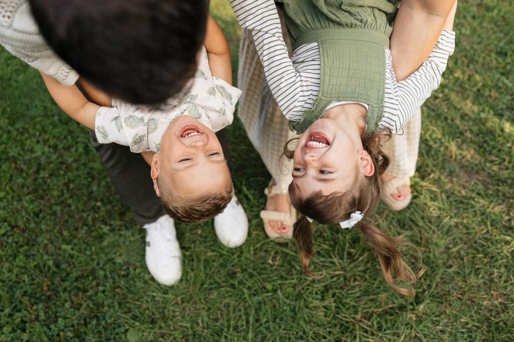 Parents dipping two kids upside down while kids laugh.