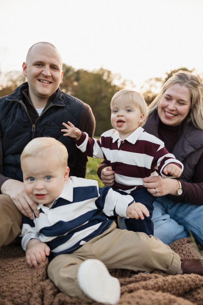 Parents snuggling with their twin toddler boys during a fall family photoshoot.